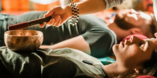 Alicia leading a couples reiki sound healing session with a singing bowl