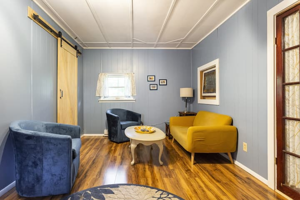 Living room with blue walls, velvet chairs and yellow sofa