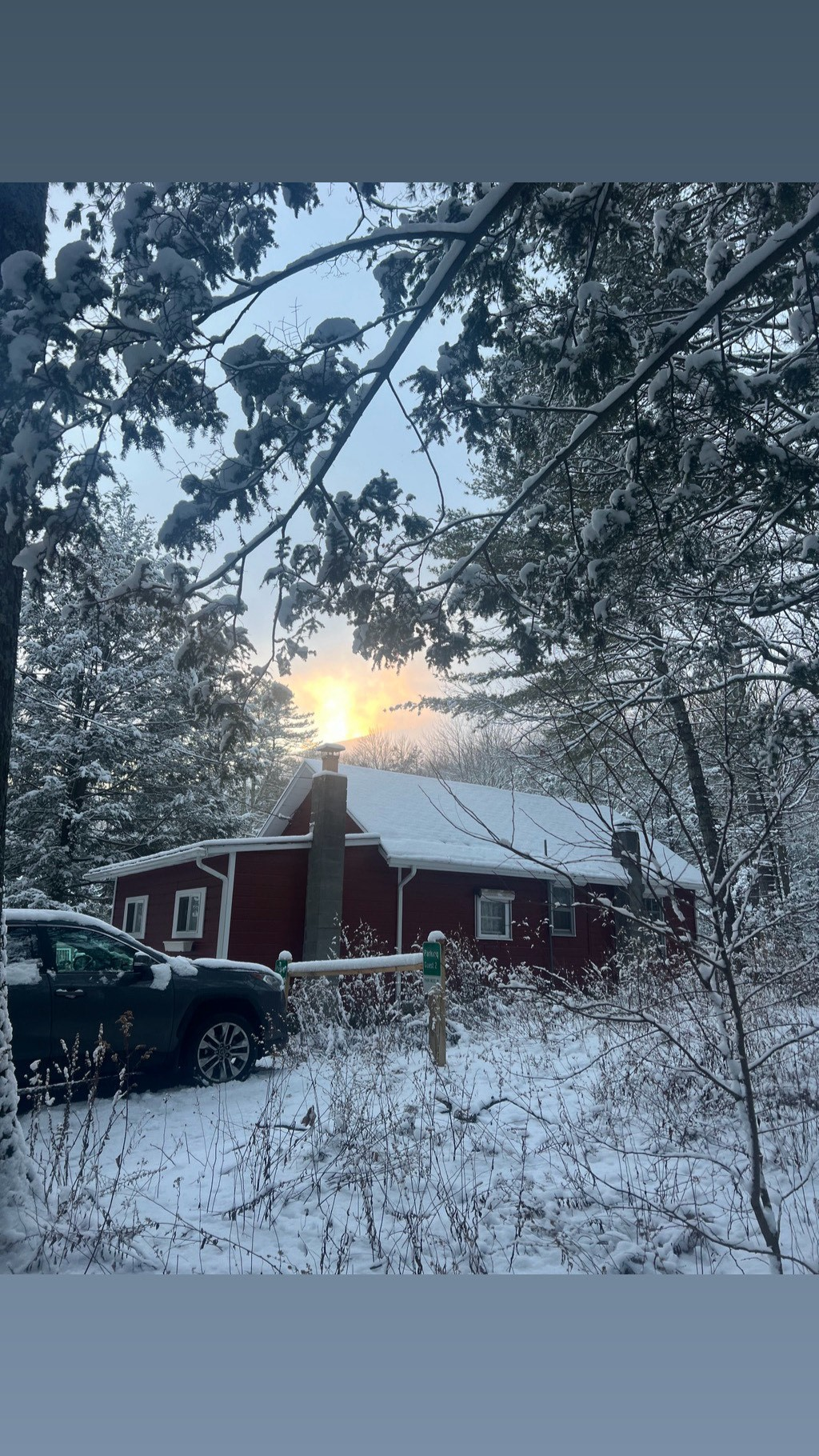 The red cottage at winter sunrise surrounded by snow-covered pines