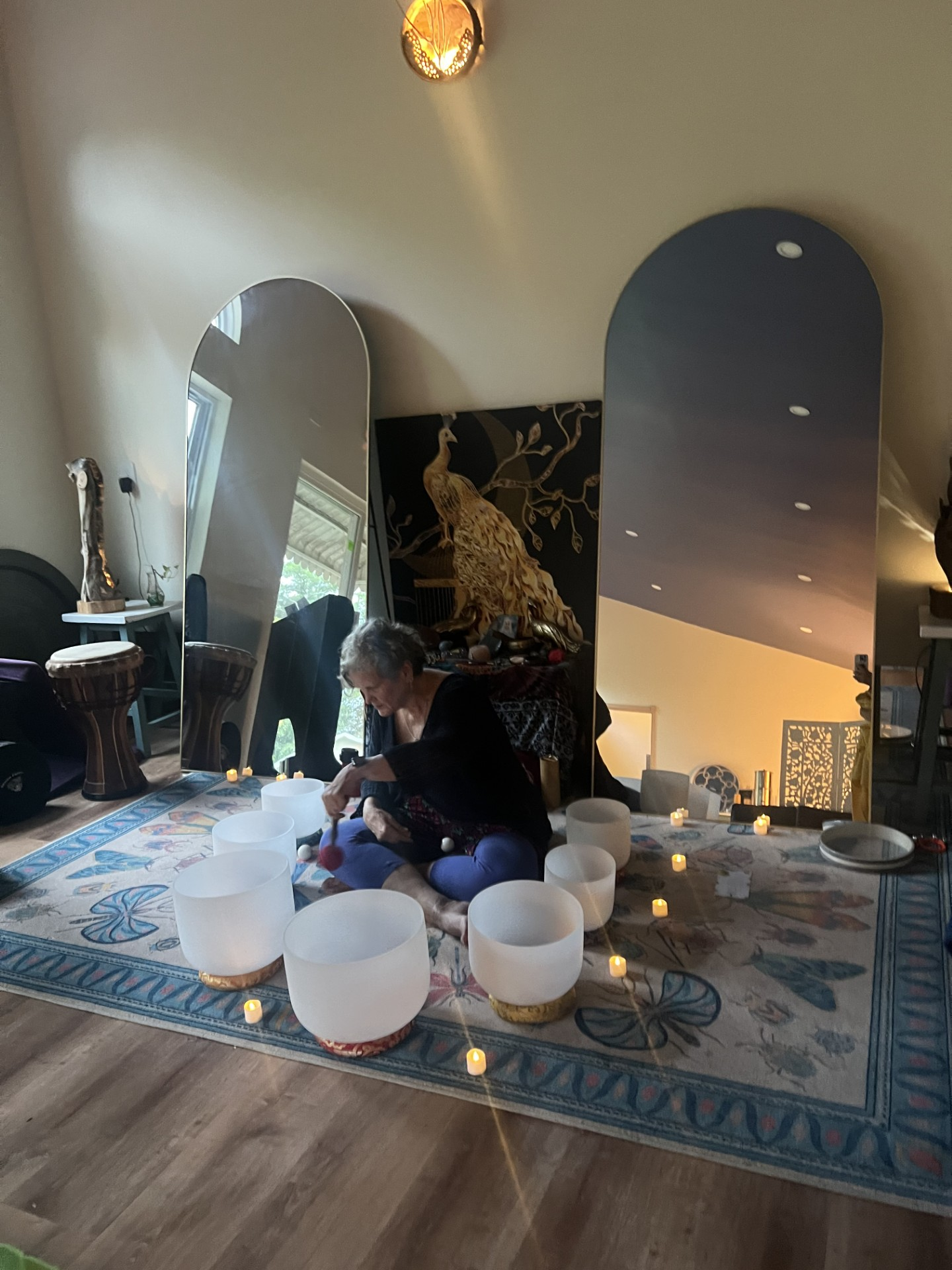 Sound healer playing crystal singing bowls by candlelight in the studio
